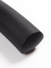 Here is a closeup image depicting a black tube resting on a white surface