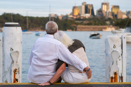 couple shares a tender embrace while sitting on a dock
