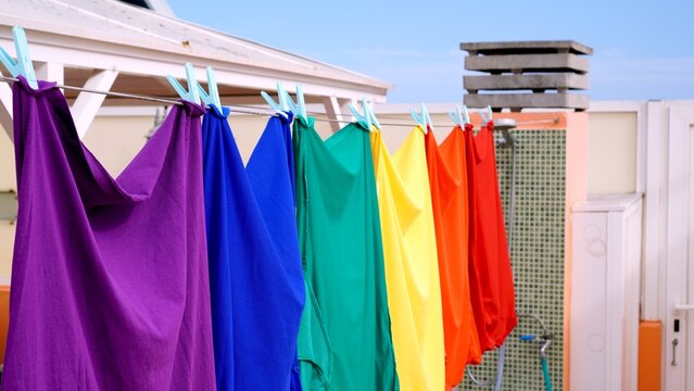 Colorful rainbow t shirts hanging on a clothesline, celebrating diversity, inclusivity, and freedom of expression during Pride Month, radiating love and acceptance under the summer sky - Powered by Adobe