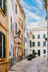 Colorful Historic Street with Traditional Buildings and Cobblestone Pavement in Ciutadella. Charming Mediterranean town, Spanish urban scene, narrow alleyway, vibrant architecture