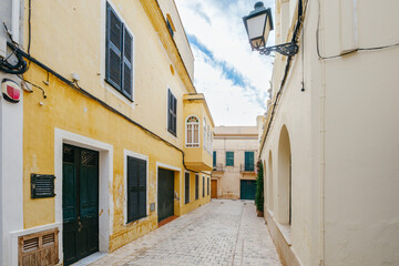 Traditional Yellow Buildings and Cobblestone Street in Ciutadella de Menorca. Charming narrow alley, Mediterranean architecture, historic town, Spanish urban scene, travel destination