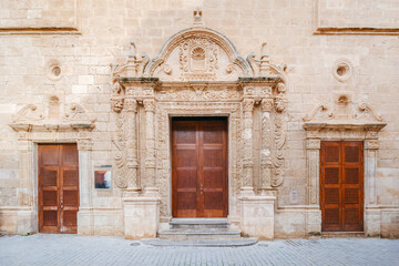 Ornate Baroque Portal and Wooden Door of Esglesia del Roser in Ciutadella de Menorca. Historic Spanish church, cultural exhibition hall, Mediterranean island, religious architecture