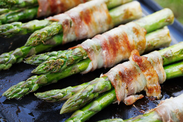 Grilled green asparagus wrapped in bacon on a  grill, plate, close-up view