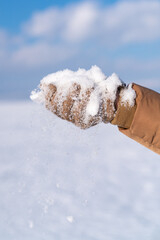 woman in brown gloves holding snow pieces in her hand.
