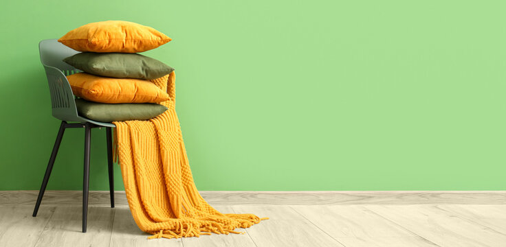 Chair with stack of pillows near green wall