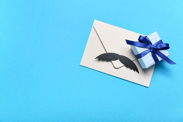 Envelope with paper mustache and gift for Father's Day celebration on color background
