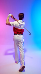 Back view of golfer finishing swing with strong posture and relaxed shoulders, standing in stylish outfit under neon light against gradient studio background. Concept of sport, tournament, leisure