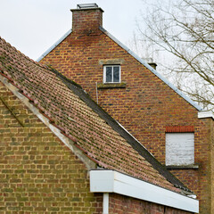 A weathered red brick gable of an old European house stands against an overcast sky. Details...
