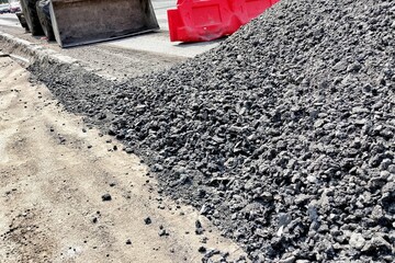 A road equipment with a bucket fills the road with gravel