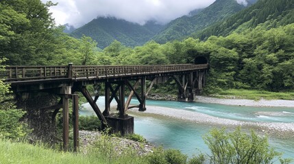 Fototapeta premium Wooden bridge over Azusa River in Kamikochi with turquoise water below and thick forest beyond, no people
