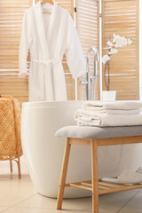 Interior of light bathroom with grey bench and bathtub