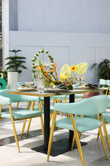 Wedding table setup with zoo floral arrangement. Stylish Dining Table in Greenhouse. Tropical Table Setting with Flowers. A stylish dining table set in a greenhouse, surrounded by lush green plants.