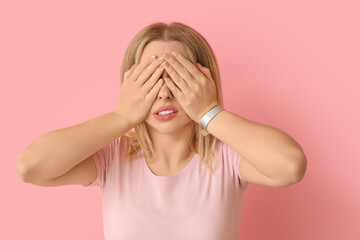 Embarrassed young woman on pink background