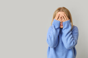 Young woman feeling shame on grey background