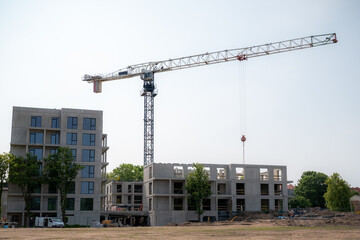 A construction site features a large tower crane with a long horizontal jib extending over...