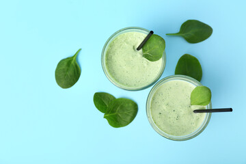 Glasses of fresh spinach smoothie on blue background