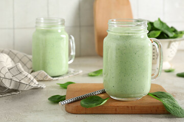 Mason jars of fresh spinach smoothie on white table