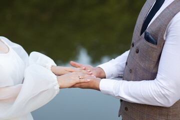 The groom holds two hands of the bride against the background of water. Gentle touches of the groom...