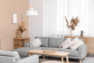 Interior of stylish living room with grey sofa, wooden table and pampas grass