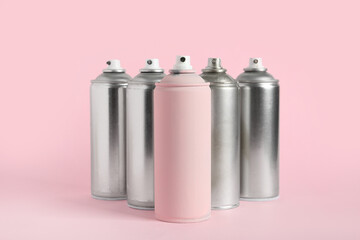 Spray paint cans on pink background