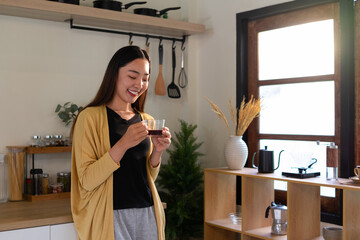 Young woman having breakfast and drinking hot coffee in the kitchen.
