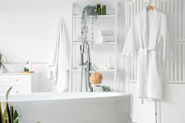 Interior of light bathroom with shelf unit, folding screen and bathtub