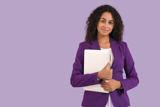 Portrait of beautiful African-American businesswoman with laptop on purple background