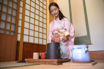 Attractive Japanese woman in traditional  kimono or yukata clothing making tea in japan house
