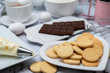Counter with ingredients: eggs, flour, beaters, and cornstarch alfajores with dulce de leche and coconut, chocolate bar with white dishes