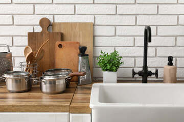 Clean dishes and kitchen utensils on wooden counter near sink