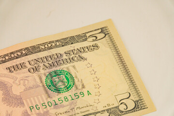 Image of a US five-dollar bill, featuring the number 5 on both sides, serial number, UNITED STATES...