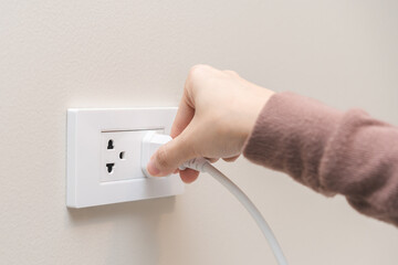 Hand of woman plugged in, unplugged electricity cord cable at home, put on or remove electric plug...