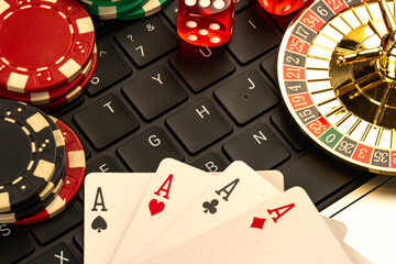 Image of casino items on a laptop keyboard, depicting themes of gambling, risk-taking, and possibly online betting or casino simulation