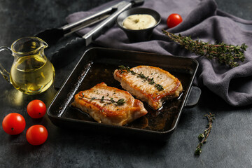 Frying pan with roasted steaks on dark background