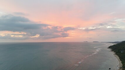 Beautiful cloudy red sunrise over sea with beach, waves and mountains in the background. Impressive structure texture in the sky