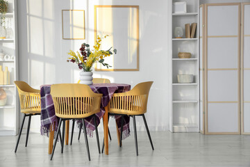 Interior of dining room with beautiful flowers and stylish purple cloth on table