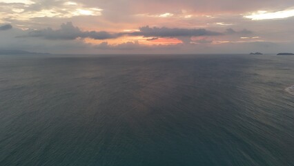 Beautiful cloudy red sunrise over sea with beach, waves and mountains in the background. Impressive structure texture in the sky