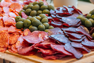 Wooden serving tray with a circular arrangement of meats salami, pepperoni, prosciutto,...