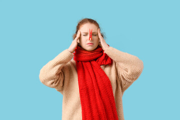 Ill young woman with clothespin on her nose suffering from headache against blue background. Stuffy...