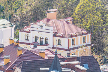 A two-story European building with a red tiled roof, white accents, and classical architectural...