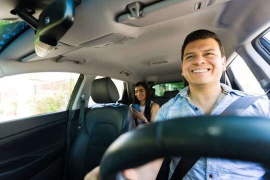 Smiling rideshare driver navigating with passenger