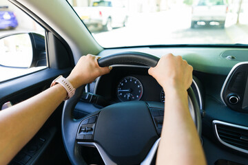Naklejka premium Closeup of hands on steering wheel while driving in city