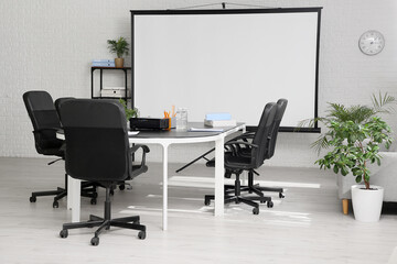Interior of conference hall with table, shelving unit and projector screen in modern office
