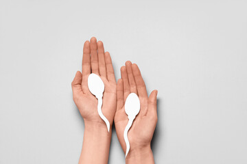 Hands with sperm cell on grey background