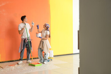 Young couple painting wall in room