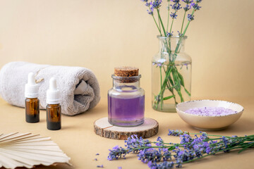 Lavender oil, bath salt and essential oil bottles on beige table. Natural herbs medicine, aromatherapy concept
