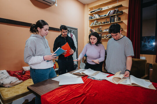 Four young actors practice their lines with scripts in a backstage room, preparing for a performance in a warm and inviting theatre environment.
