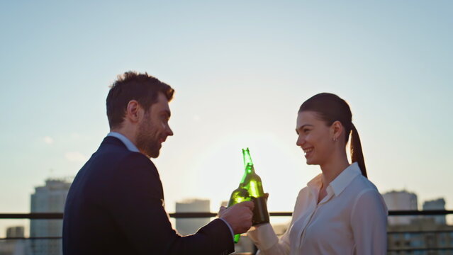 Friends drinking beer sunset rooftop relaxing together after workday closeup.