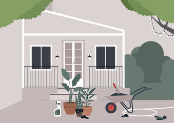 A modern two-story home with a small front porch displays potted plants, gardening tools, and a wheelbarrow with soil, suggesting an afternoon spent tending to the small garden