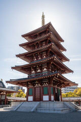 Shitenno-ji Gojunoto - A five-story pagoda stands tall against a clear blue sky in Osaka, Japan. Its intricate red wooden structure and golden details showcase traditional Japanese craftsmanship.